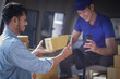 © Tj - Deliver service. Man With Box in Car Outdoors Delivery Man in uniform holds parcel and phone car outdoors Delivery man taking parcels from The Delivery service.