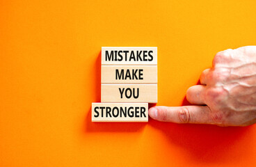Wall Mural - Mistake make stronger symbol. Concept words Mistakes make you stronger on wooden blocks. Beautiful orange table orange background. Businessman hand. Business mistake make stronger concept. Copy space.