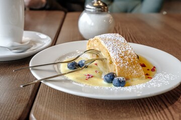 a piece of delicious strudel stuffed with apples and cinnamon on a plate sprinkled with sweet sauce.