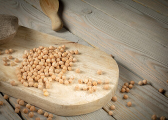 Wall Mural - Country style. Chickpeas scattered on a kitchen cutting board on a wooden table