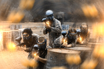 Wall Mural - Five paintball players in camouflage and protective masks aims with guns outdoors