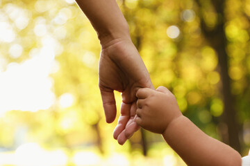 daughter holding mother's hand outdoors, closeup. happy family