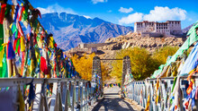 Suspension Bridge Over A River.The Way To Stakna Gompa With Fall Foliage In Leh, Ladakh, India. Narrow Bridge And Colorful Tibetan Prayer Flag With Winter Blue Sky. Beautiful Landscape Of India.
