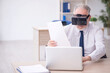 © Elnur - Old male employee wearing virtual glasses at workplace