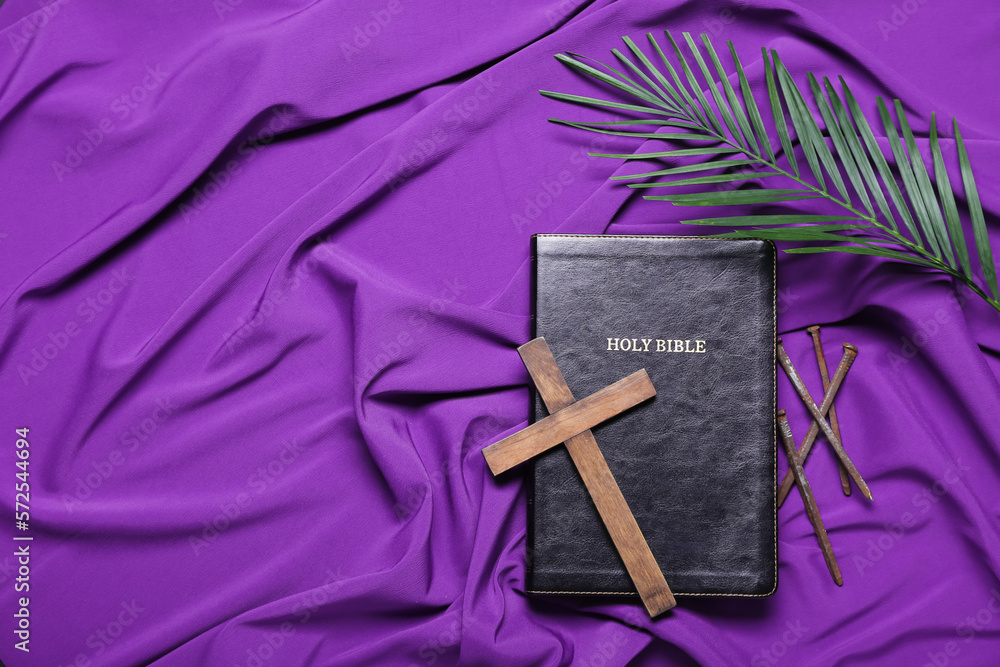 Holy Bible with cross, nails and palm leaf on purple fabric background. Good Friday concept