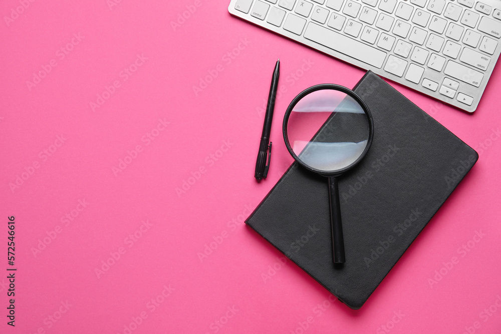 Notebook, pen, magnifier and keyboard on pink background. World Poetry Day celebration