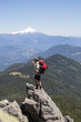 © Cavan Images - Hiker takes photo on summit in front of volcano