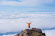 © Cavan Images - Man stretches arms overhead, mountain summit