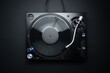 Flat lay photo of DJ turntable playing vinyl record on black background. Professional analog record player shot directly from above