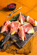 Prosciutto ham with slices of melon and fresh thyme. Orange background. Top view