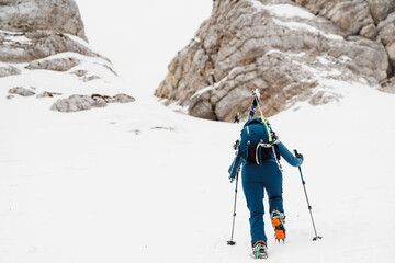 One lonely ski tourer climbing up the snowy mountain, view from behind