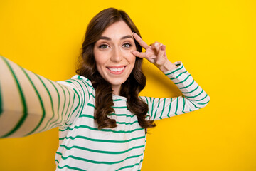 Poster - Photo of pretty positive person toothy smile take selfie show v-sign near eye isolated on yellow color background