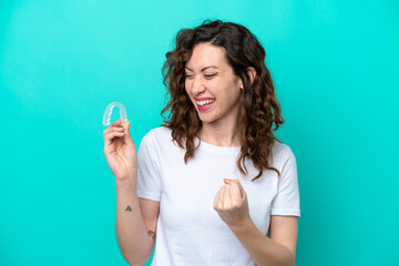 Poster - Young caucasian woman holding a envisaging isolated on blue background celebrating a victory