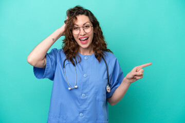 Wall Mural - Young nurse caucasian woman isolated on blue background surprised and pointing finger to the side