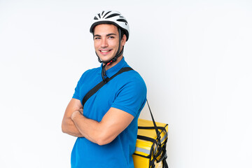 Wall Mural - Young caucasian man with thermal backpack isolated on white background with arms crossed and happy