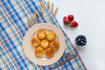 Wall Mural - Cottage cheese pancakes, syrniki fritters strawberry, blueberry in yellow plate. Gourmet Breakfast