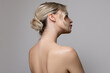 Young beautiful woman stands on her side with bare shoulders and back. Concept of hair and makeup, skin and body care