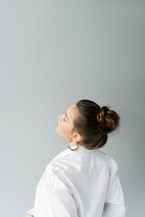 Wall Mural - young model in white shirt and hoop earring posing isolated on grey with copy space.