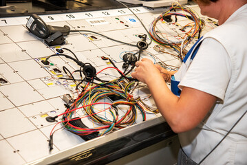 Wall Mural - Hands of employees who check the quality of the wiring for cars at a modern plant on a special stand at the production shop