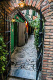 Fototapeta Uliczki - Arch of a secret entrance to a small courtyard	
