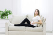 © Andrii - Pregnant woman sitting on white sofa. Concept of pregnant woman at home