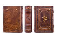 Aged Brown Leather Book With The Eye Of Horus In The Center Of The Front Cover And The Book Spine. The Cover Is Embossed, Gilded, Have Metal Corners, Raised Ribs On The Spine. 
