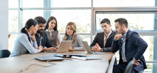 Wall Mural - Group of business people on a meeting in office. Focused partners looking at laptops and planning new business strategy.