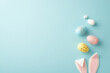 Easter concept. Top view photo of easter bunny ears and colorful eggs on isolated pastel blue background with copyspace