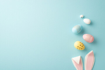 Wall Mural - Easter concept. Top view photo of easter bunny ears and colorful eggs on isolated pastel blue background with copyspace