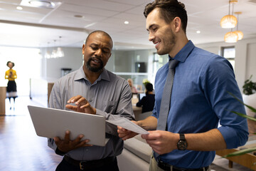 Wall Mural - Image of diverse male colleagues working and talking in office