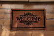 Door mat with word Welcome on wooden floor, top view