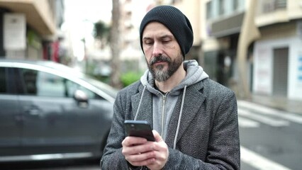 Canvas Print - Young bald man using smartphone with serious expression at street