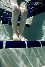 An Underwater View Of A Young Child Stepping Into A Pool.