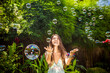 © Cavan Images - Young Asian womans blowing bubbles.