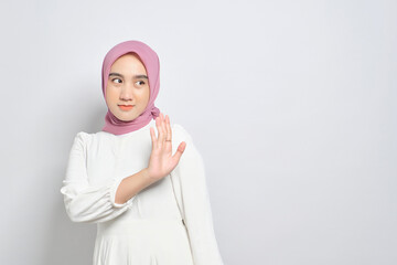 Wall Mural - Serious young Asian Muslim woman making stop gesture and showing rejection isolated over white background