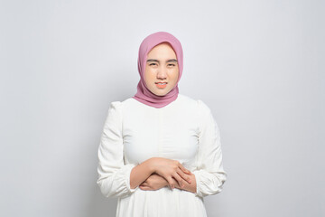 Wall Mural - Unhealthy young Asian Muslim woman touching belly, having stomach pain isolated over white background