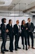 © CinemaF - Full-length view of international business team. Multiethnic group of coworkers standing in office with smile
