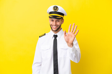 Wall Mural - Airplane caucasian pilot isolated on yellow background saluting with hand with happy expression