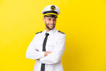 Wall Mural - Airplane caucasian pilot isolated on yellow background with arms crossed and happy