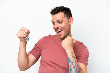 Wall Mural - Young caucasian man holding home keys isolated on white background celebrating a victory