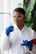 © ArtSys - African American female scientist is working in laboratory, making test and experiment with micro biology technology. Chemical glass beaker with blue liquid. Women in science, scientific research
