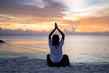 Wall Mural - woman doing yoga at sunset on tropical beach