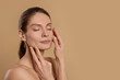 © New Africa - Woman massaging her face on beige background. Space for text