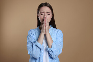 Wall Mural - Woman with clasped hands praying on beige background