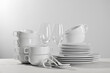 © New Africa - Set of clean dishware and glasses on white wooden table against light background