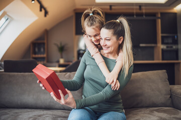 Happy mother is getting gift from her daughter.