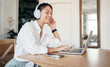 © muse studio - Headphones and laptop A woman comfortably spending time listening to an audiobook in the app and studying online.