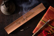 Overhead view of burning incense stick on wooden holder, notebook with pen and tibetan bell