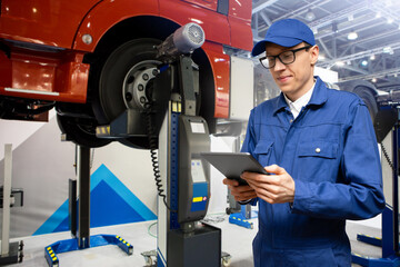 Poster - Serviceman with digital tablet on the background of the truck in the garage	