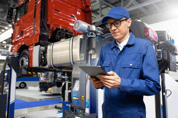 Poster - Serviceman with digital tablet on the background of the truck in the garage	